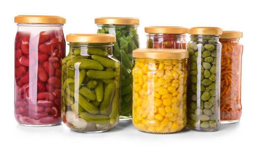 白色背景下装有不同蔬菜和豆类罐头的罐子照片